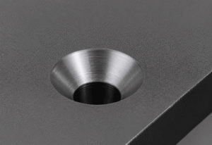 Close-up of a 90-degree countersink hole machined into a metal plate