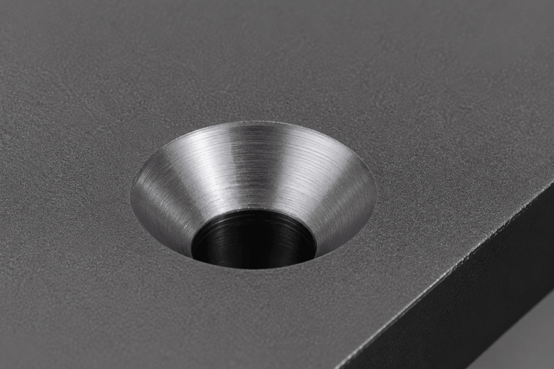 Close-up of a 90-degree countersink hole machined into a metal plate